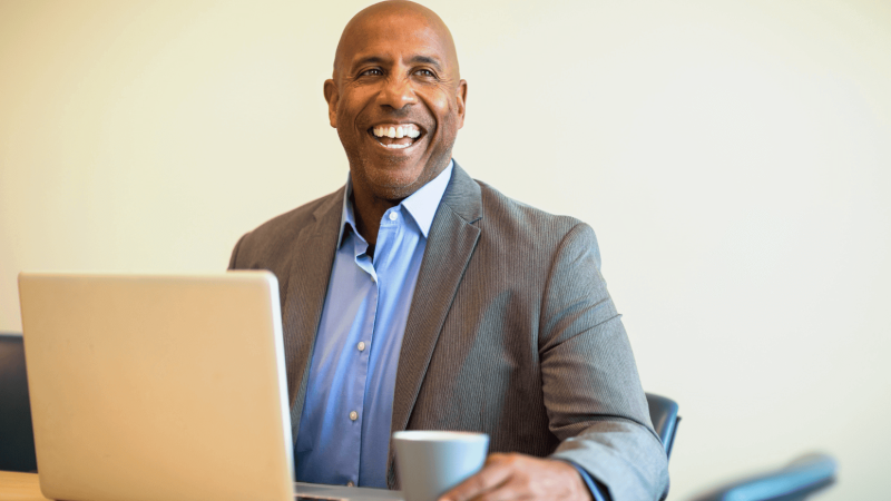 Homme noir souriant devant un ordinateur