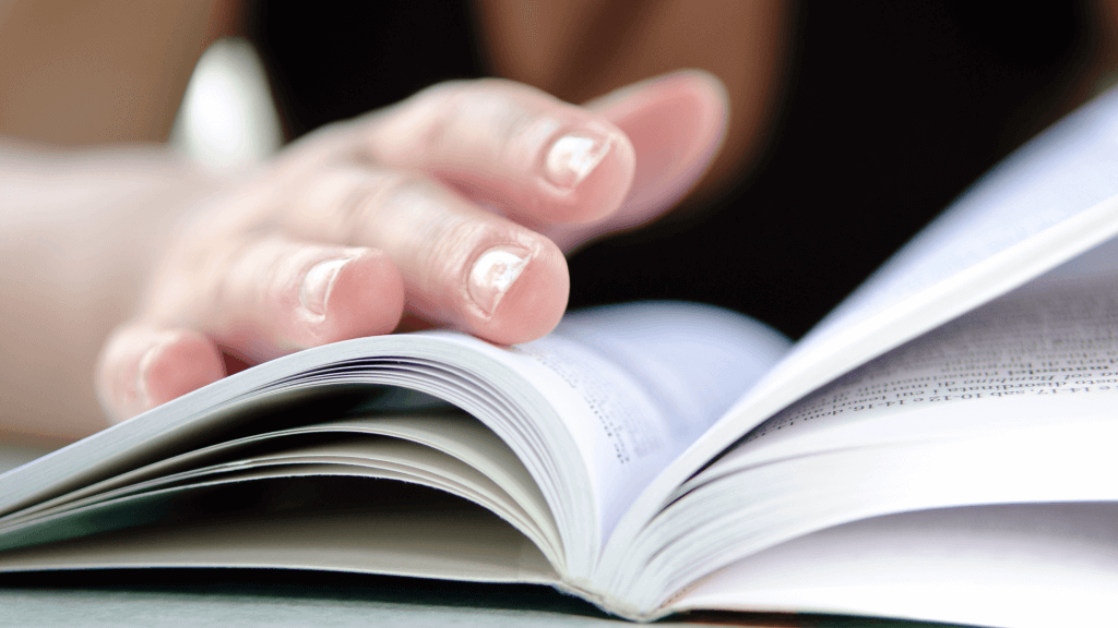 livre-ouvert-feuillete Main qui feuillète un dictionnaire à la recherche de la définition de l'outplacement.