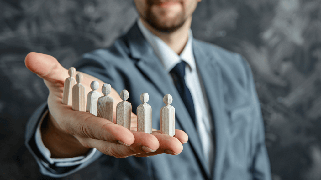 Homme avec des figurines en bois dans la main pour signifier le management en entreprise.