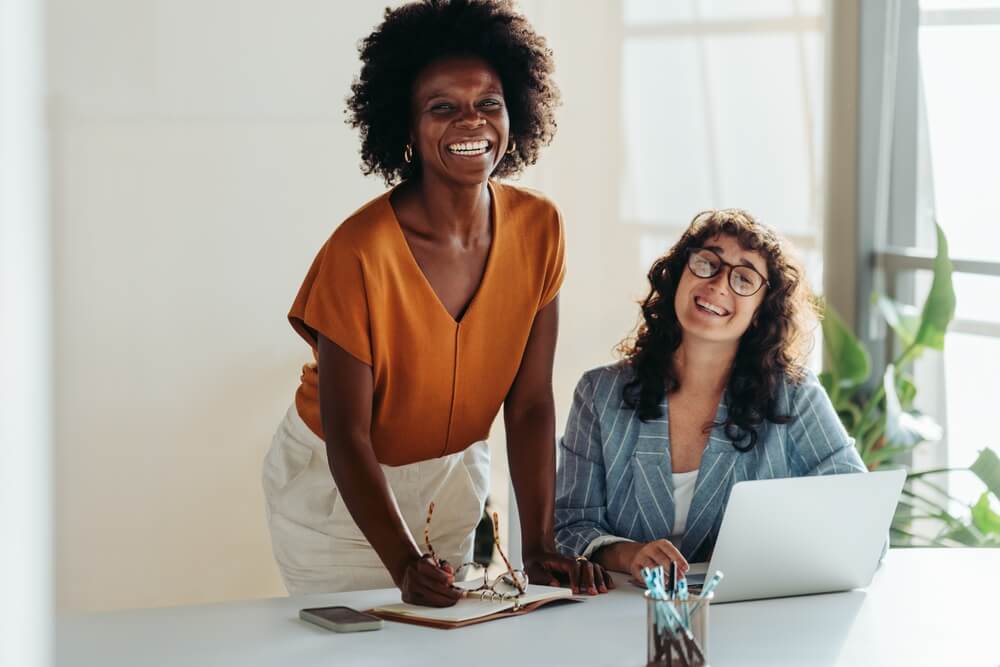 Two,Diverse,Professional,Women,Smile,At,The,Camera,While,Working